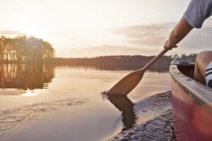 Person canoeing on river at sunrise