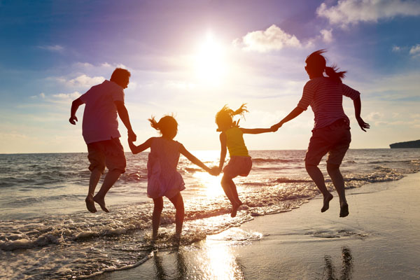 Family holding hands jumping on beach