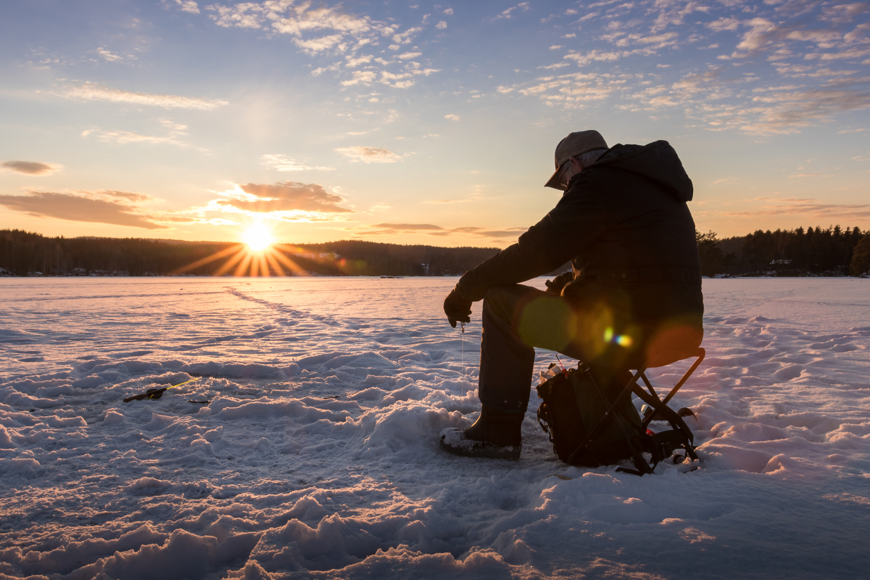 guy ice fishing at sunset