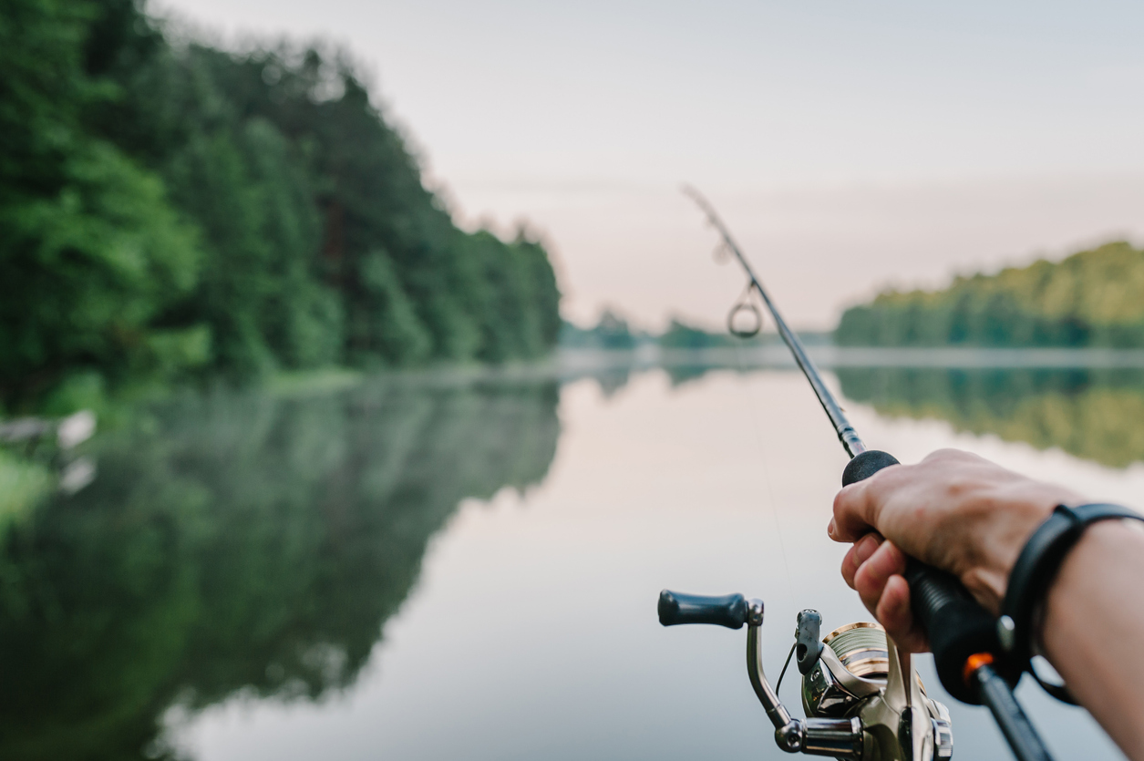 Person casting fishing pole on river