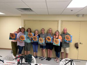 Group of ladies showing off art made in class