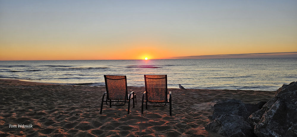 Chairs on beach on shoreline at sunrise